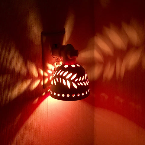 round night light in white with wavey leaf designs and yellow orange interior